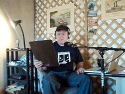 K.L. at the mic, with headphones on, reading the text for the voice work audition