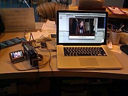 K.L.'s MacbookPro sitting on box office counter at The Dayton Theatre Guild with a DV mini-cassette camcoder hooked into i, and DV footage being transferred into the FinalCut project for the DIVIDING THE ESTATE podcast.